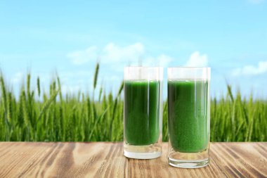 Shots of juice and wheat grass field on background clipart