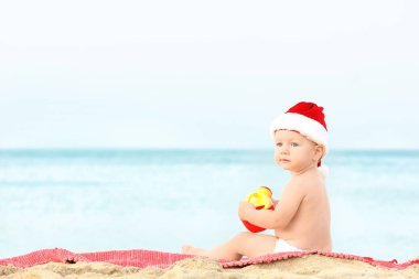 Noel Baba şapkalı plajda şirin çocuk