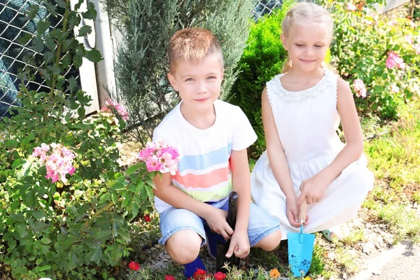 Niedliche kleine Kinder pflanzen Blumen im Garten — Stockfoto