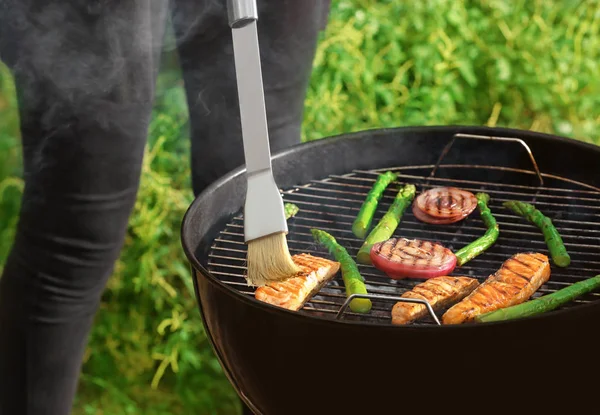 Žena vaření losos plátky se zeleninou na grilu venku — Stock fotografie