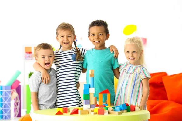 Leuke kinderen spelen met blokken op tafel binnen — Stockfoto