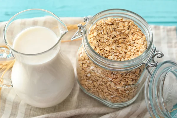 Jar with oatmeal flakes and pitcher of milk — Stock Photo, Image