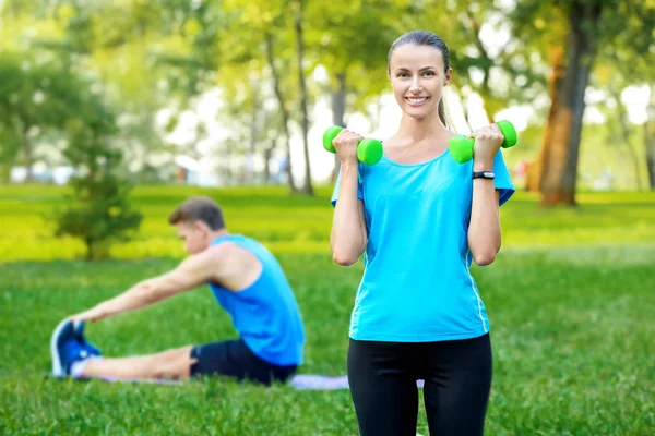 Joven pareja deportiva haciendo ejercicios en el parque verde —  Fotos de Stock