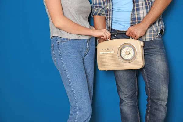 Ung man med kvinna som håller retro radio på färgbakgrund — Stockfoto