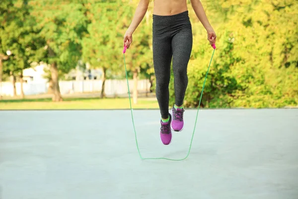 Young sporty woman jumping rope outdoors — Stock Photo, Image