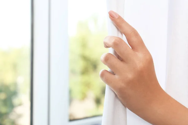 Mulher desenhando cortinas brancas dentro de casa — Fotografia de Stock