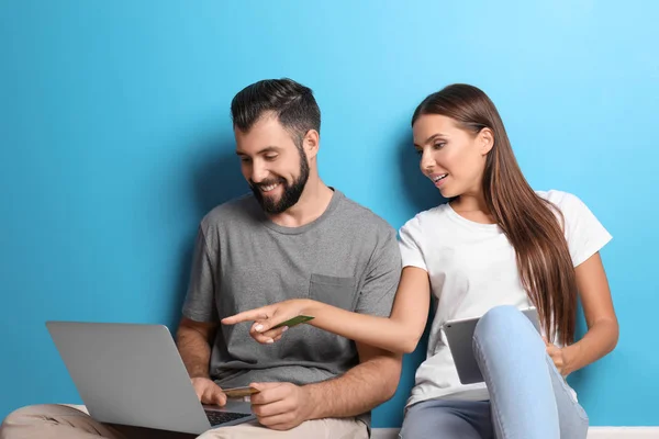 Jeune couple avec ordinateur portable et tablette près du mur de couleur. Concept de magasinage Internet — Photo