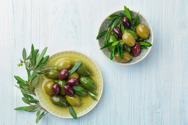 Plate and bowl with olives on white wooden background — Stock Photo, Image