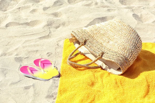 Toalha de praia amarela, com saco e chinelos na areia — Fotografia de Stock