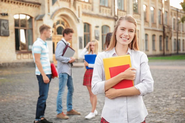 Jonge vrouwelijke student met vrienden in de buurt van universiteitsgebouw — Stockfoto