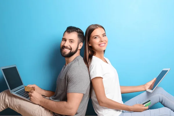 Renk arka plan üzerinde dizüstü ve tablet bilgisayar ile genç çift. Internet alışveriş kavramı — Stok fotoğraf