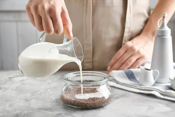 Vrouw gieten yoghurt in glazen pot met chia zaden — Stockfoto