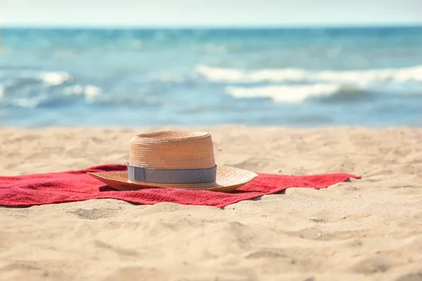 Червоний пляжний рушник і капелюх на піску — стокове фото