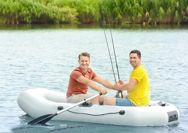 Dos hombres que pescan del barco inflable en río — Foto de Stock