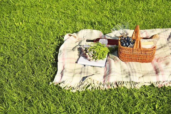 Samenstelling met picknickmand op deken buitenshuis — Stockfoto