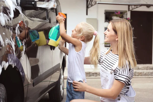Vrouw met dochter wassen autootje buitenshuis — Stockfoto