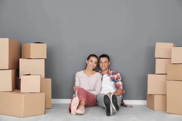 Gelukkige jonge paar zittend op de vloer in hun nieuwe appartement in de buurt van Verhuisdozen — Stockfoto