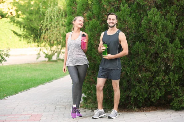 Joven hombre y mujer en ropa deportiva descansando al aire libre — Foto de Stock