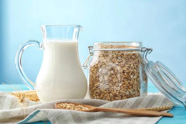 Jar with oatmeal flakes and pitcher of milk — Stock Photo, Image