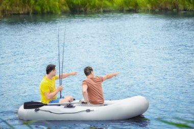 İki adam Nehri üzerinde şişme tekneden Balık tutma