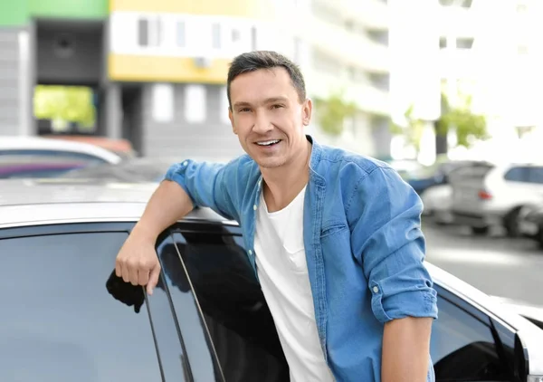 Человек в повседневной одежде стоит рядом с машиной — стоковое фото