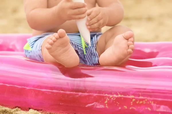 Niedliche Baby-Junge sitzt auf aufblasbarer Matratze am Strand — Stockfoto