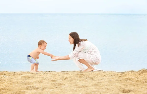 Felice madre con il piccolo figlio sulla spiaggia — Foto Stock