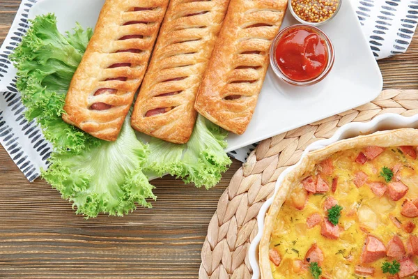 Samenstelling met smakelijke braadpan en worst rolt op tafel — Stockfoto