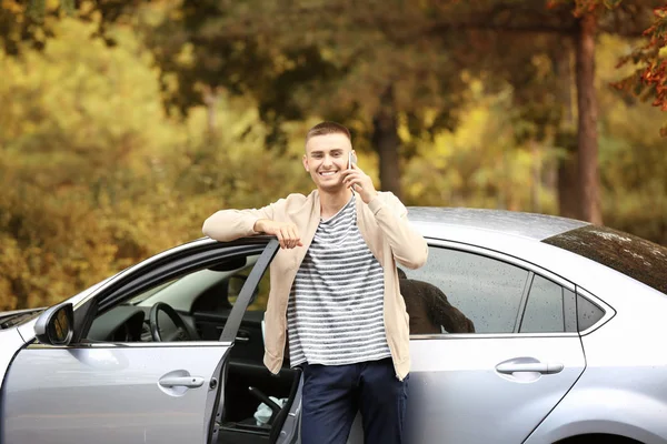 Bel giovanotto che parla al cellulare vicino all'auto nel parco — Foto Stock