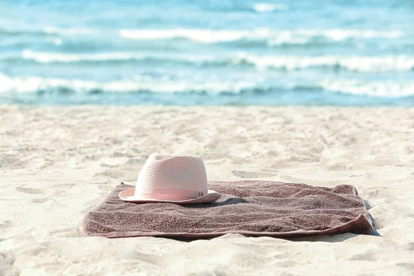 Toalha de praia marrom com chapéu na areia — Fotografia de Stock
