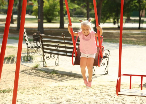 Adorable little girl on swing at playground — Stock Photo, Image