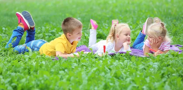 Adorables niños pequeños acostados en una manta en el parque — Foto de Stock