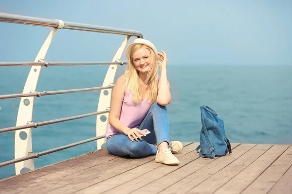 Beautiful young woman sitting on pier — Stock Photo, Image
