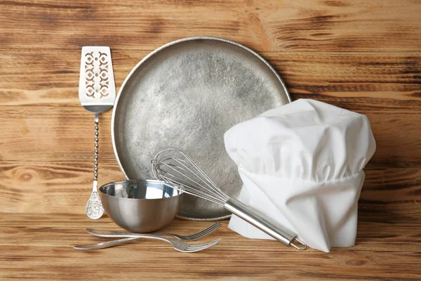 Kitchen utensils and chef hat on table — Stock Photo, Image