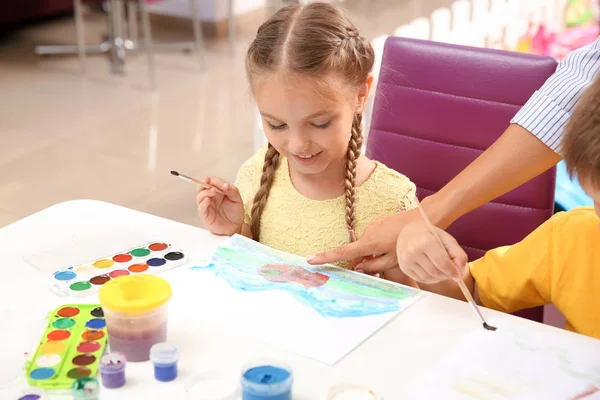 Little girl at painting lesson in classroom