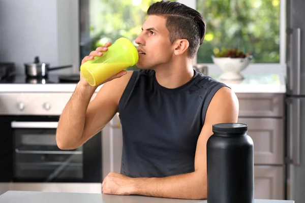 Joven bebiendo batido de proteínas en la cocina — Foto de Stock