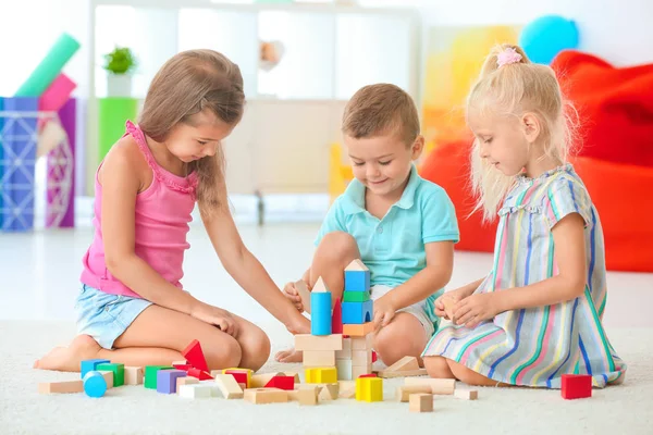 Niedliche Kinder spielen mit Bauklötzen drinnen — Stockfoto