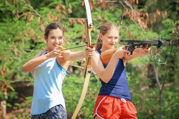 Unga kvinnor skjuta pilbåge och armborst utomhus — Stockfoto