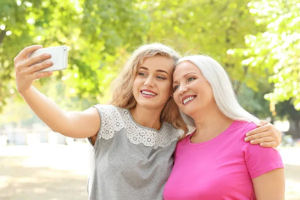 Mujer joven y su madre tomando selfie en el parque —  Fotos de Stock