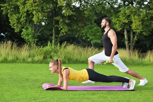 Joven pareja deportiva haciendo ejercicios en el parque verde —  Fotos de Stock
