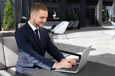 Yakışıklı adam ile onun laptop açık havada oturup takım elbiseli