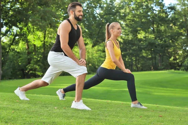 Jovem casal desportivo fazendo exercício no parque verde — Fotografia de Stock