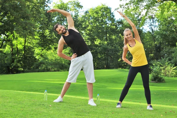 Ung sporty par laver motion i grøn park - Stock-foto