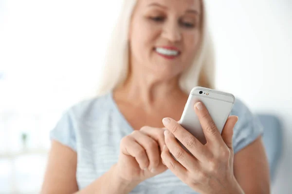 Старша жінка використовує мобільний телефон вдома — стокове фото