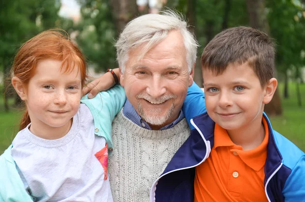 Счастливый пенсионер со смешными внуками в парке — стоковое фото