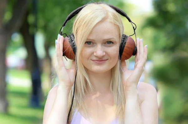 Bella giovane donna che ascolta musica nel parco — Foto Stock