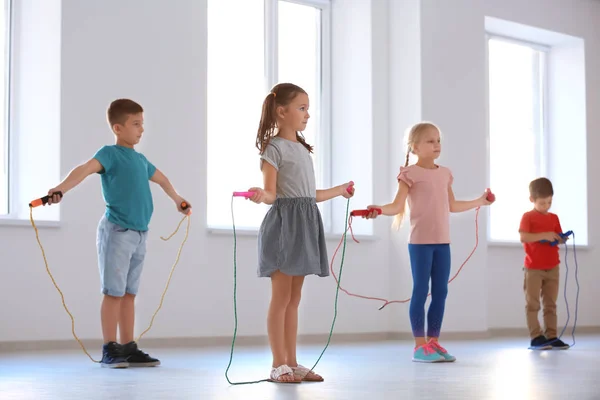 Adorable children skipping rope indoors — Stock Photo, Image