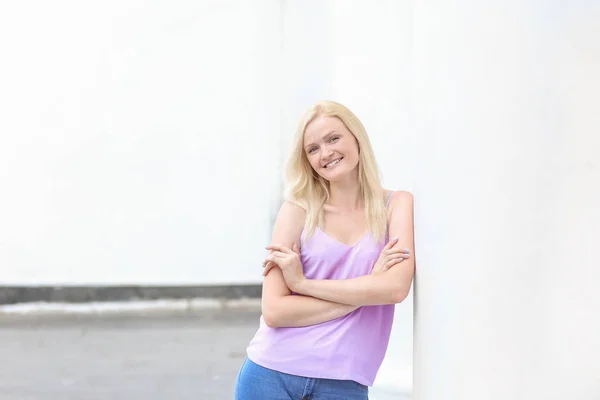 Mooie jonge vrouw in de buurt van kolom buitenshuis — Stockfoto