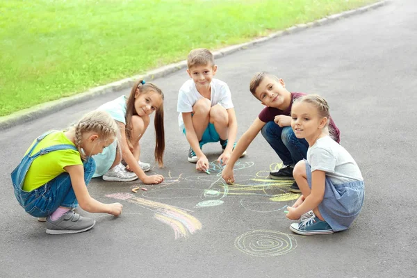 Lindos niños pequeños dibujando con tiza sobre asfalto, al aire libre — Foto de Stock