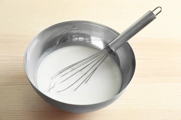 Metal bowl with yogurt and whisk for making pudding — Stock Photo, Image